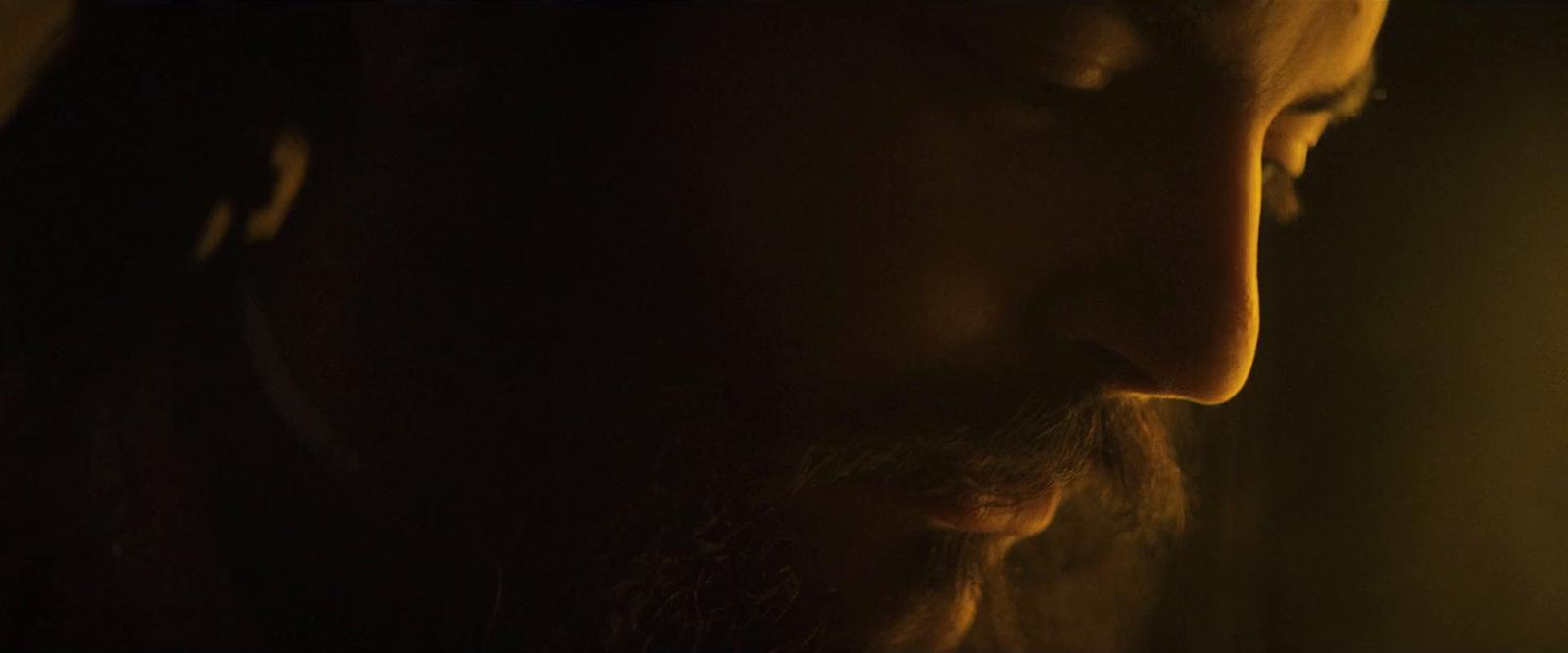 a man with long hair and beard standing in a dark room