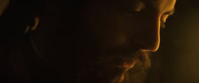 a man with long hair and beard standing in a dark room