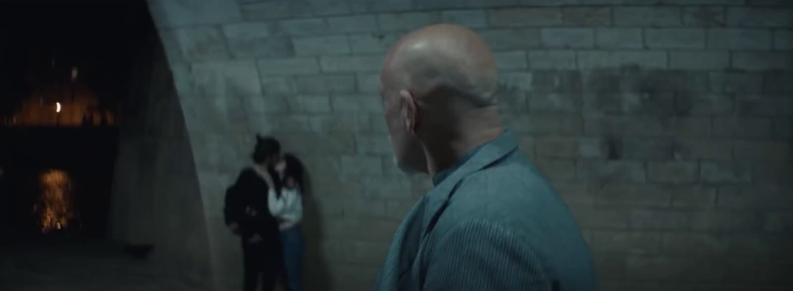a man standing next to a woman in front of a brick wall