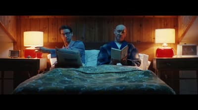a couple of men sitting on top of a bed