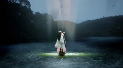 a woman in a white dress standing in a body of water