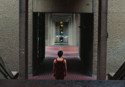 a woman in a red dress walking down a hallway