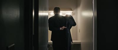 a man in a black suit standing in a doorway