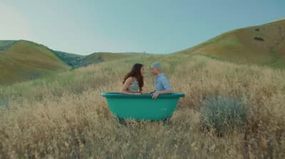a man and a woman sitting in a tub in a field