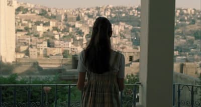 a woman standing on a balcony looking at a city