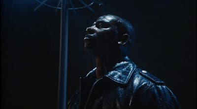 a man in a leather jacket looking up at a light