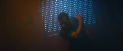 a man standing in front of a window in a dark room
