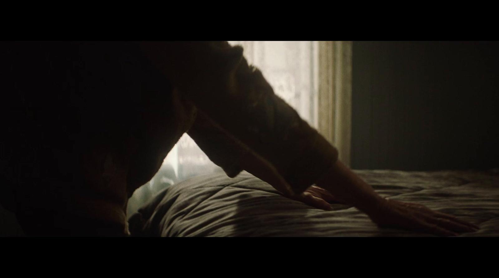 a person bending over on a bed in a dark room