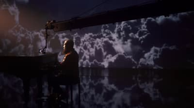 a man sitting at a desk in front of a projection of clouds