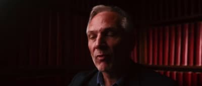 a man in a dark room with red curtains