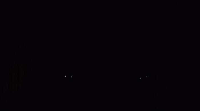 a black and white photo of a clock in the dark
