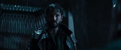 a man in a leather jacket standing in a dark room