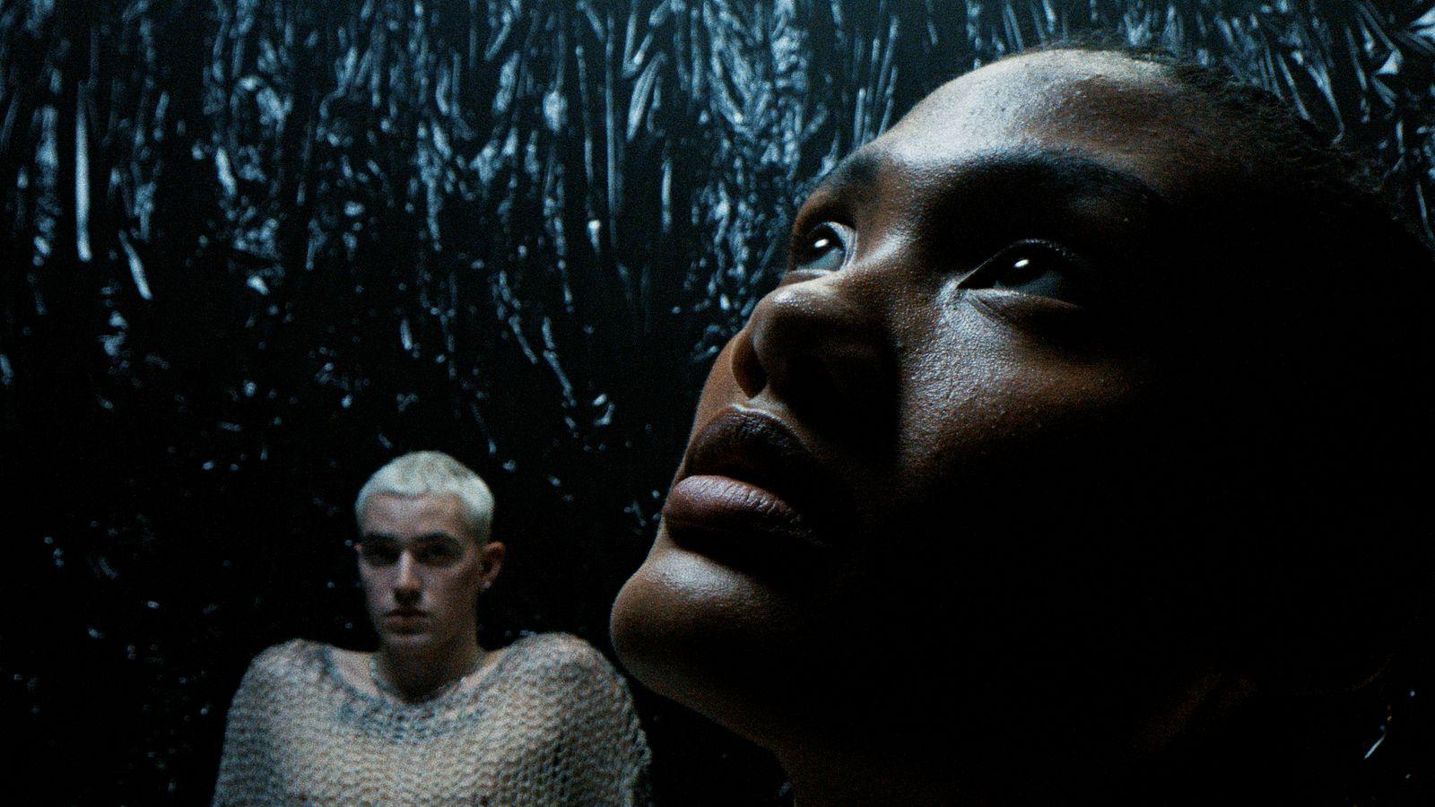 a woman standing next to a man in a dark room