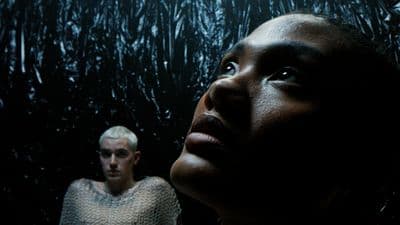 a woman standing next to a man in a dark room