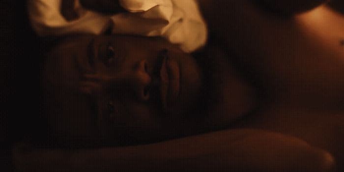 a man laying in bed with a white shirt on
