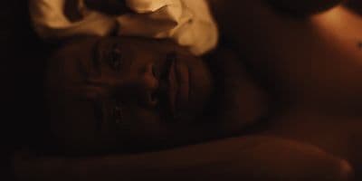 a man laying in bed with a white shirt on