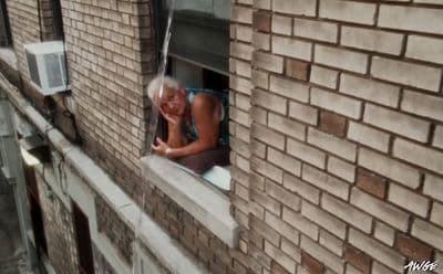 a woman looking out of a window of a brick building