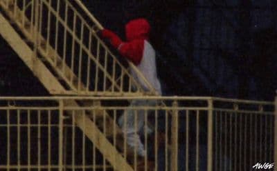 a person in a red hoodie climbing up a stair case