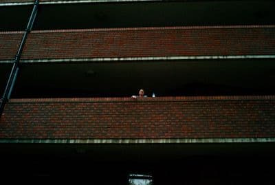 a woman standing on a balcony next to a brick building