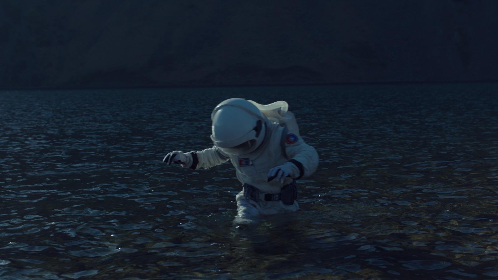 a man in a space suit wading in a body of water