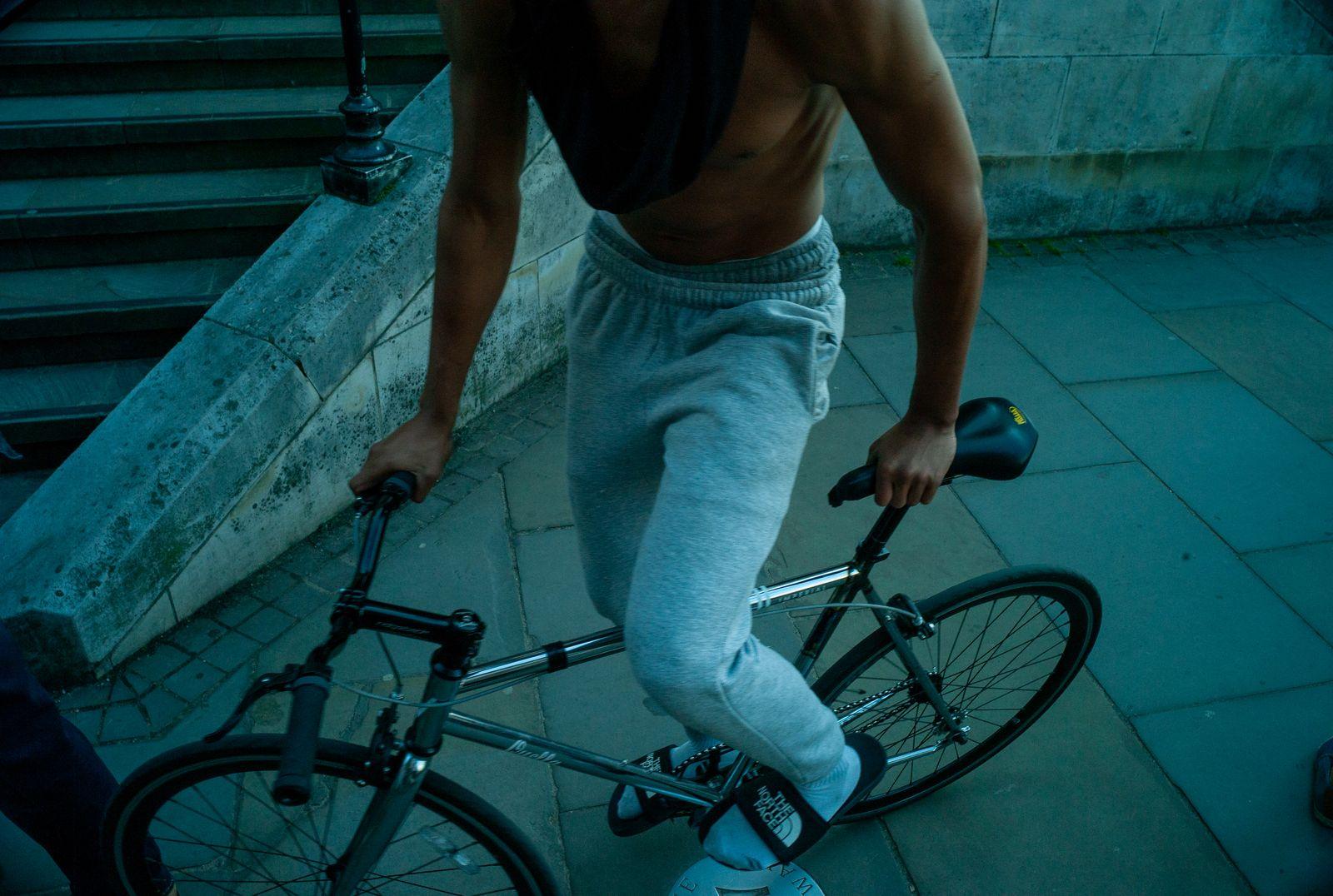 a shirtless man riding a bike down a street