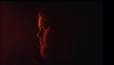 a man with a beard standing in the dark