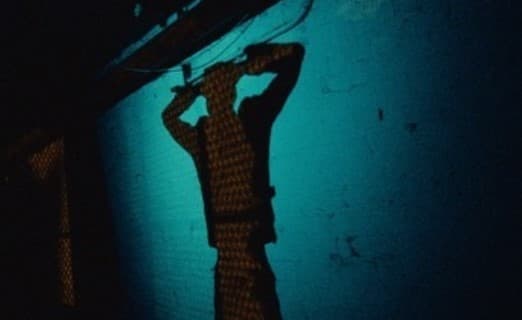 a person standing in the dark with their hands on their head