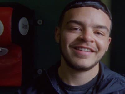 a man smiling in front of a green wall