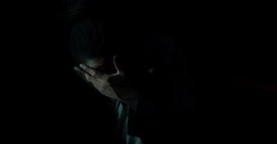 a man in the dark covering his face with his hands