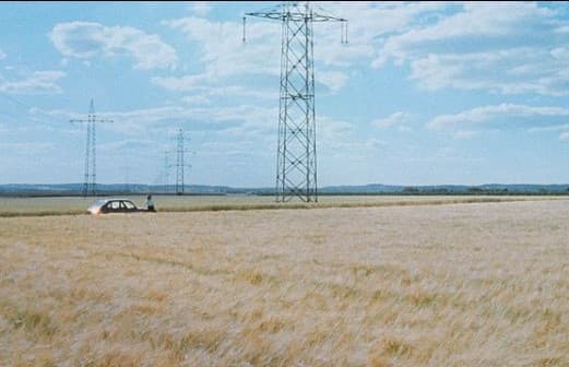a car is parked in a field with power lines in the background