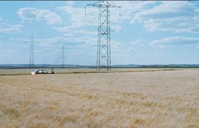 a car is parked in a field with power lines in the background