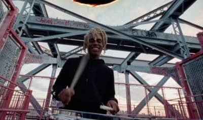 a man holding a drum in front of a metal structure