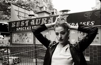 a black and white photo of a woman standing in front of a restaurant