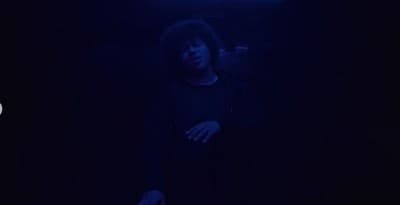 a man standing in the dark with his arms crossed
