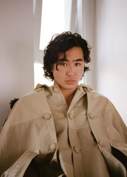 a man sitting in a chair with a coat over his shoulders