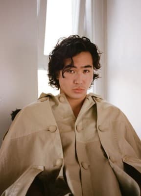 a man sitting in a chair with a coat over his shoulders