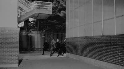a black and white photo of people walking down a sidewalk