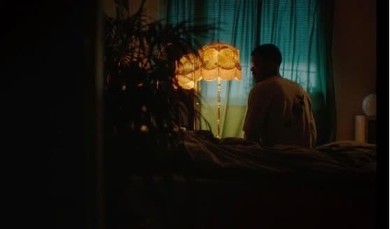 a man standing in front of a lamp in a dark room