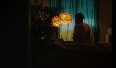 a man standing in front of a lamp in a dark room