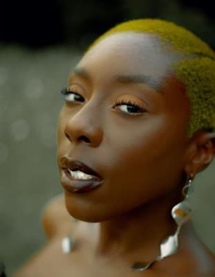a woman with yellow hair and earrings on her head