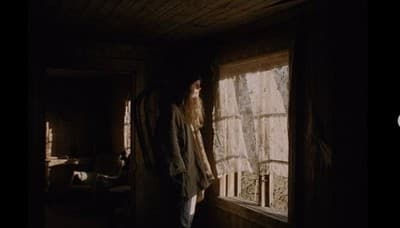 a man standing next to a window in a dark room