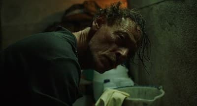a man with his head down leaning against a wall
