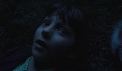 a young boy laying on the ground in the dark