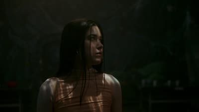 a woman standing in the dark with her hair blowing in the wind