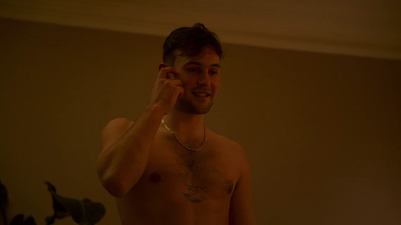 a shirtless man holding a cell phone to his ear