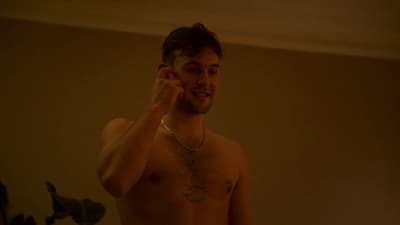 a shirtless man holding a cell phone to his ear