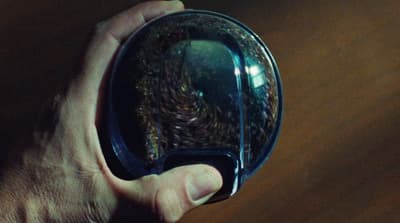 a hand holding a mirror with a reflection of a person in it