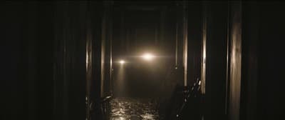 a dark hallway with a light at the end of it