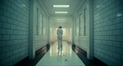 a man walking down a hallway in a white suit