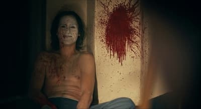 a man with a bloody face sitting in a room
